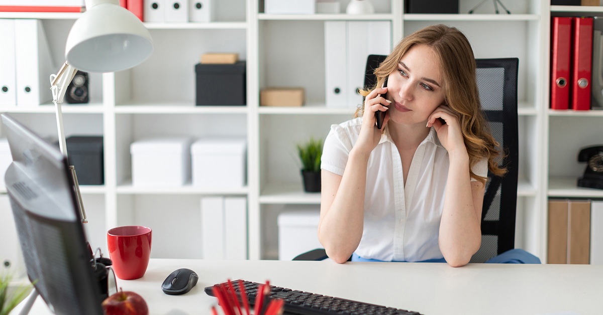 Beautiful young girl is sitting in the office and talking on the phone.